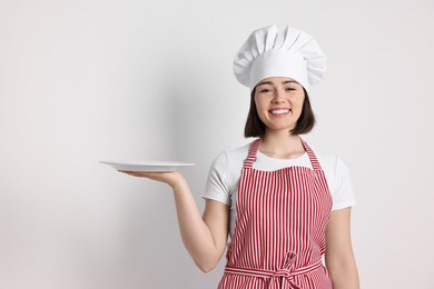 Happy confectioner with plate on light grey background