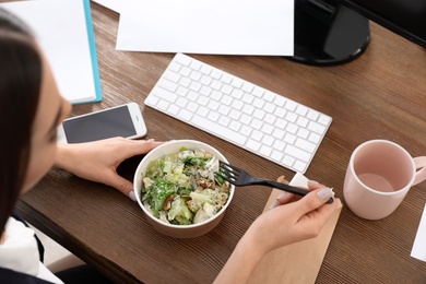 Office employee having salad for lunch at workplace, closeup. Food delivery