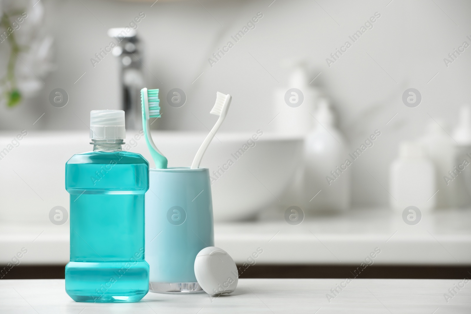 Photo of Mouthwash, toothbrushes and dental floss on white countertop in bathroom. Space for text