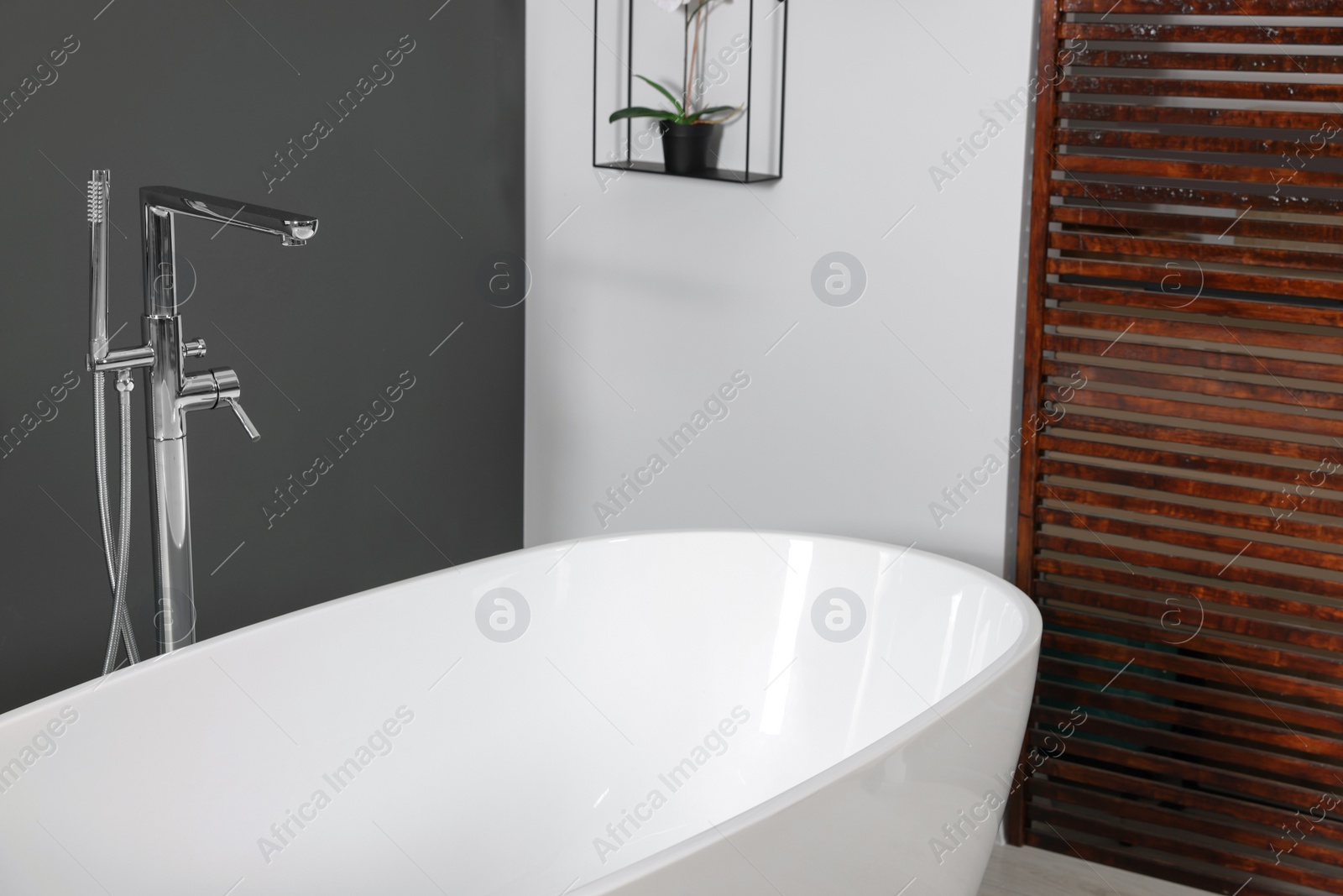 Photo of Stylish ceramic tub and modern tab in bathroom