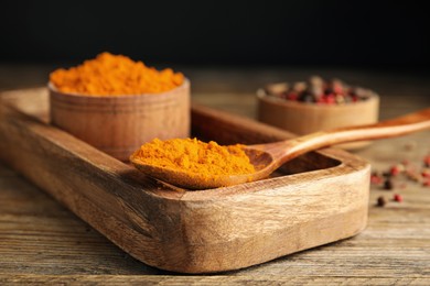 Photo of Spoon and bowl with saffron powder on wooden table, closeup