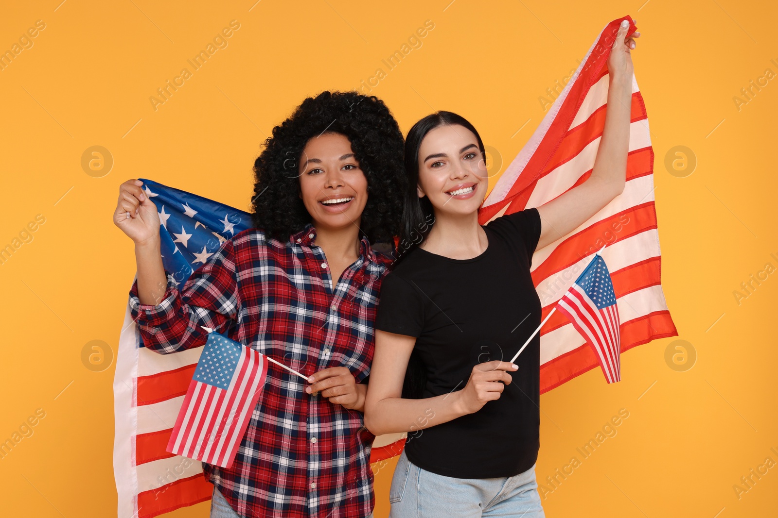 Photo of 4th of July - Independence Day of USA. Happy women with American flags on yellow background