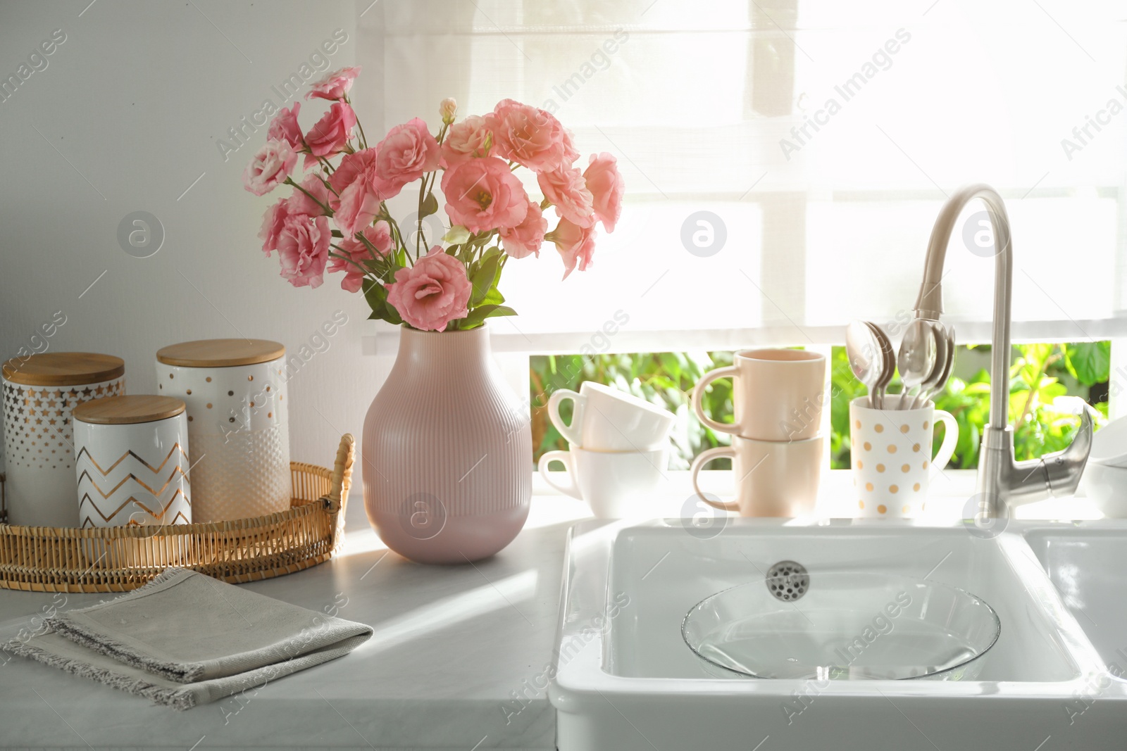 Photo of Vase with flowers on countertop near sink against window in kitchen