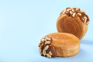 Tasty puff pastry. Supreme croissants with chocolate paste and nuts on light blue background, closeup. Space for text