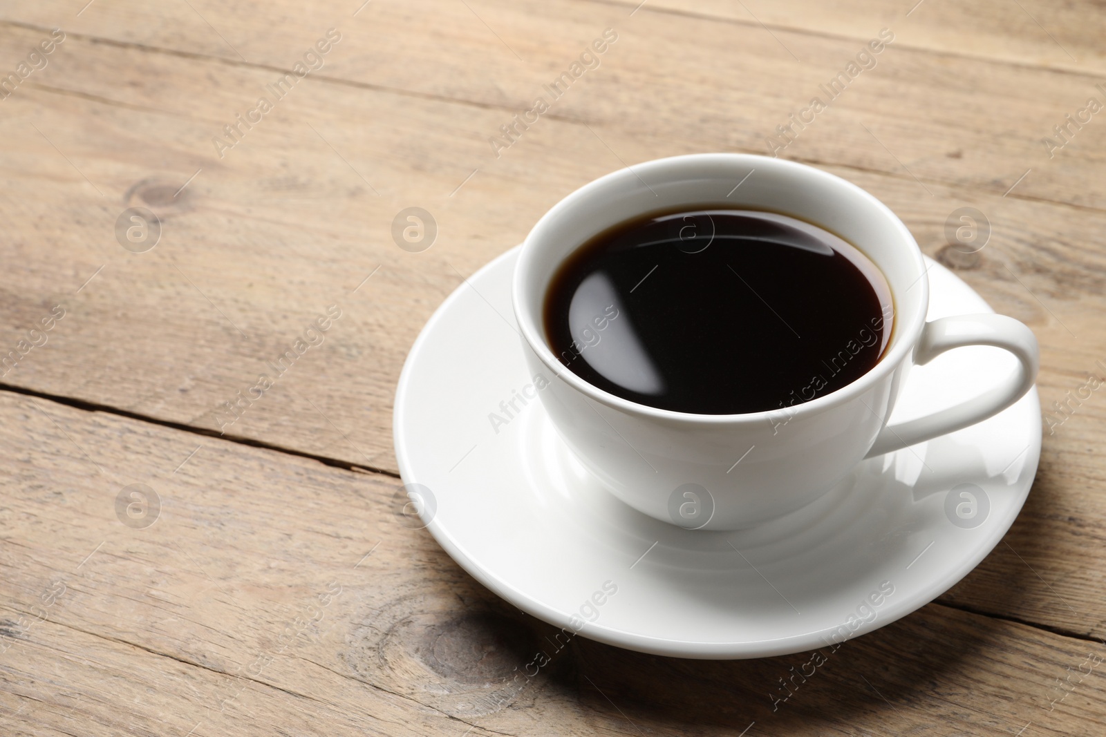 Photo of Cup of aromatic coffee on wooden table. Space for text