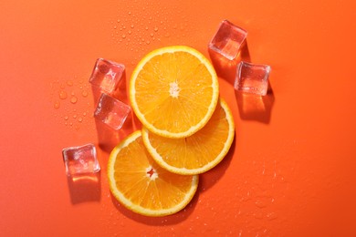 Slices of juicy orange and ice cubes on terracotta background, flat lay