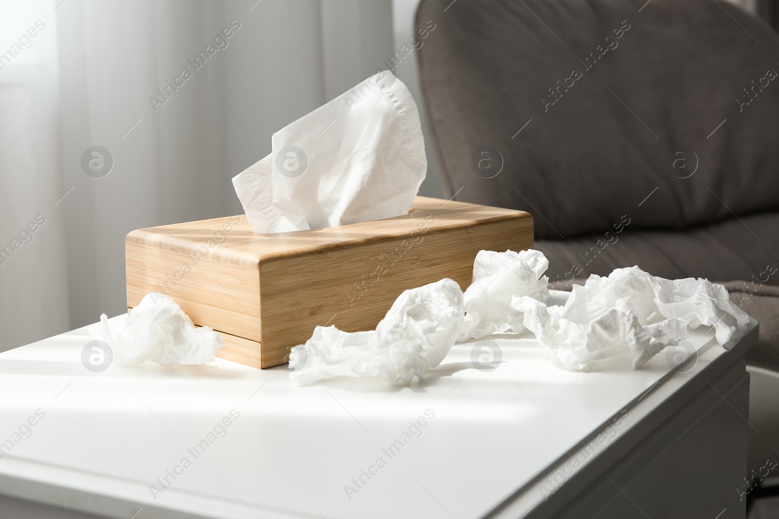 Photo of Used paper tissues and wooden holder on table indoors