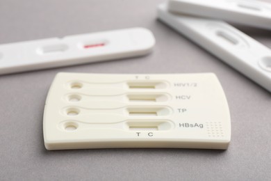 Photo of Different disposable express tests on light grey background, closeup