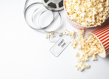 Photo of Popcorn, tickets and movie reel on white background, top view. Cinema snack