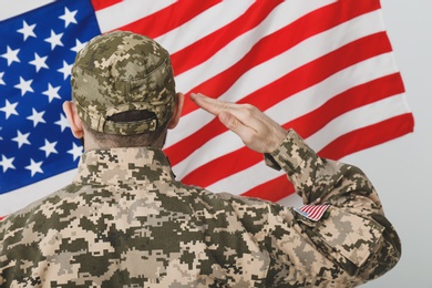 Soldier in uniform and United states of America flag on white background, back view