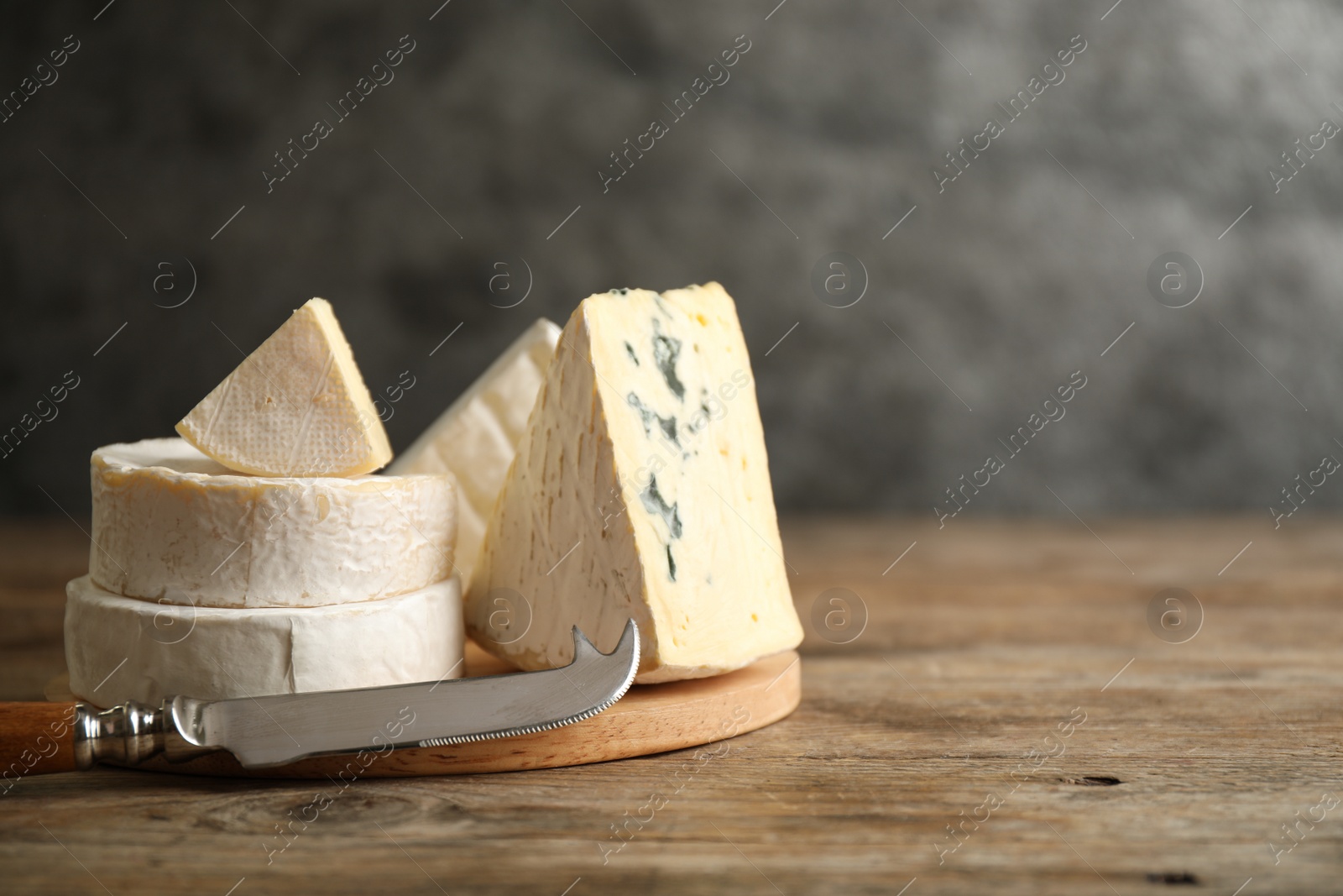 Photo of Different types of cheese and knife on wooden table. Space for text