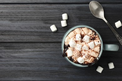 Photo of Cup of aromatic hot chocolate with marshmallows and cocoa powder served on dark gray wooden table, flat lay. Space for text