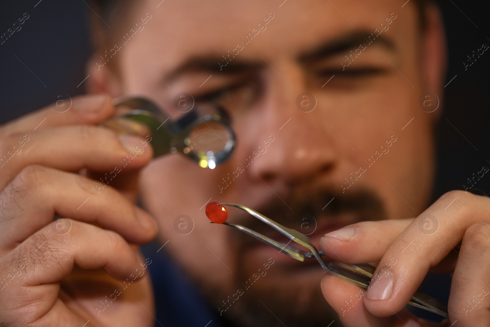 Photo of Jeweler working with gemstone on blurred background, closeup