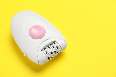 Photo of Modern epilator on yellow background, closeup. Space for text