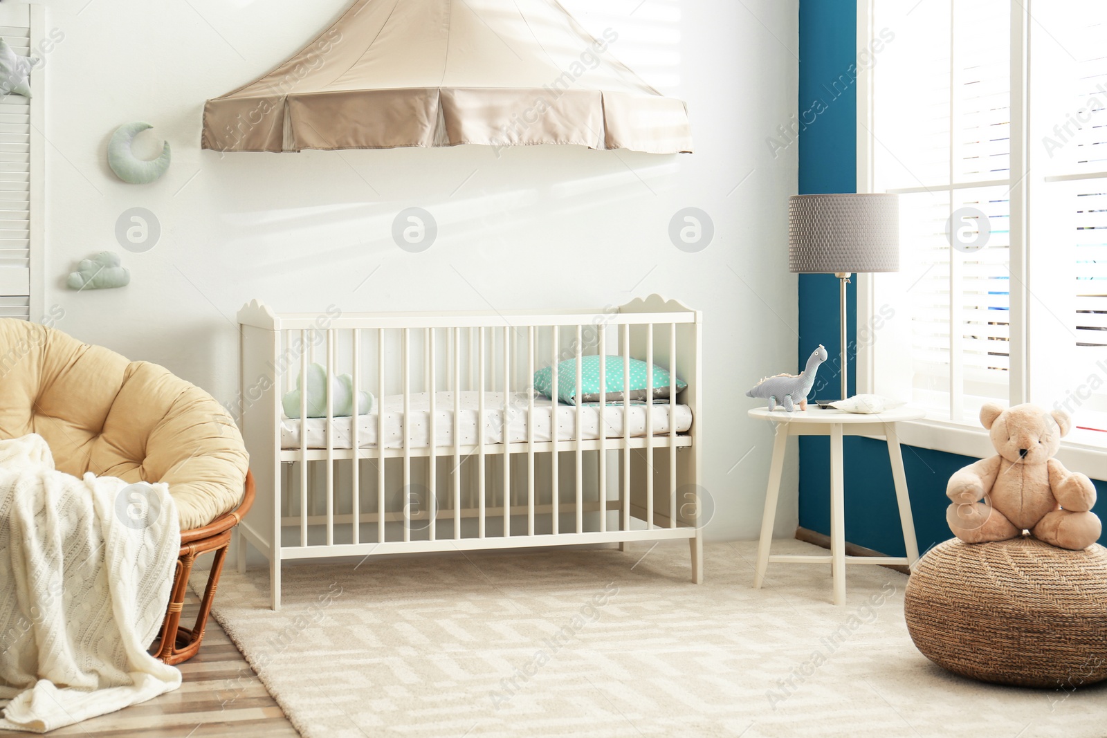 Photo of Cute nursery interior with comfortable crib near white wall