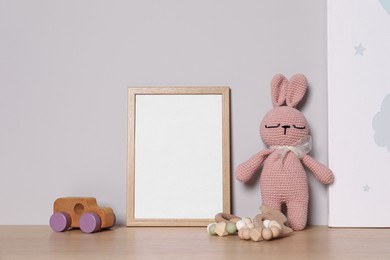 Photo of Empty square frame and different toys on wooden table