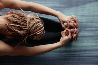 Photo of Young woman practicing yoga on mat, top view