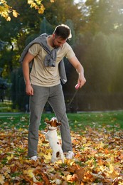 Photo of Man with adorable Jack Russell Terrier in autumn park. Dog walking