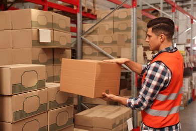 Worker stacking cardboard boxes in warehouse. Wholesaling