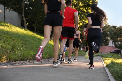 Photo of Group of people running outdoors, back view