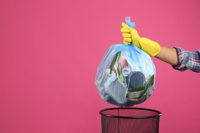 Photo of Woman taking garbage bag out of bin on pink background, closeup. Space for text