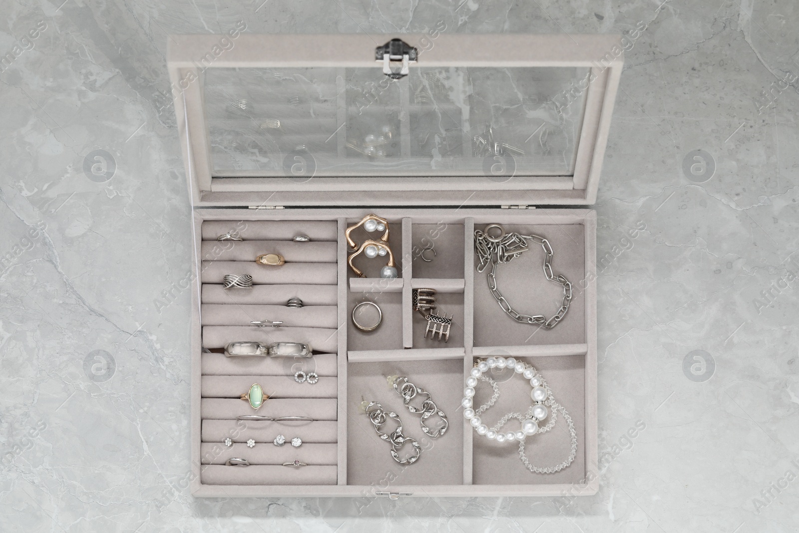 Photo of Jewelry box with many different accessories on light grey table, top view