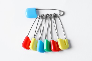 Photo of Colorful safety pins on white background, flat lay