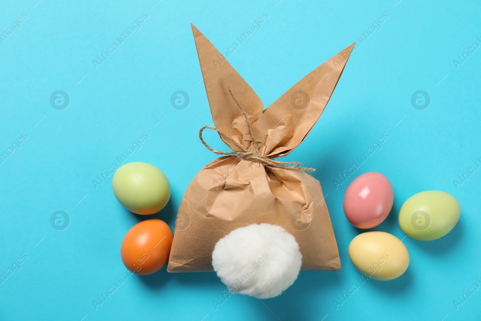 Photo of Easter bunny gift bag and dyed eggs on color background