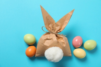 Photo of Easter bunny gift bag and dyed eggs on color background