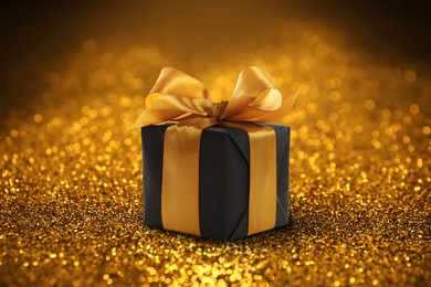 Beautiful gift box on shiny golden glitters. Bokeh effect 