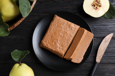 Photo of Black plate with quince paste on dark wooden table, flat lay