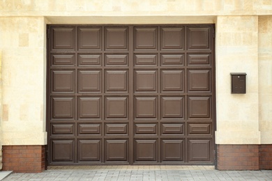 Photo of Large brown gate in modern wall of building