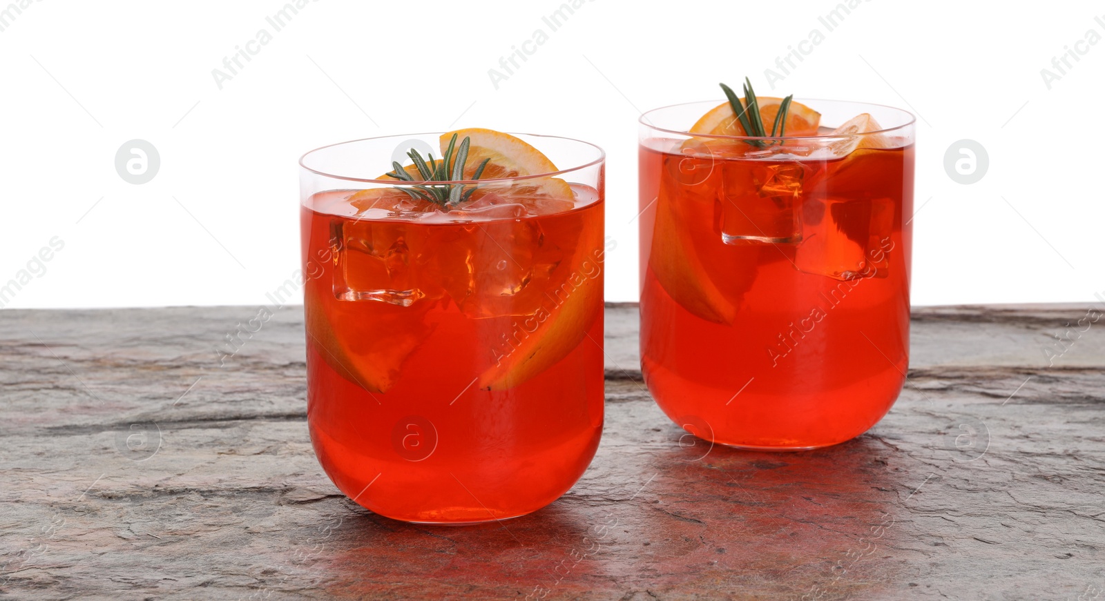 Photo of Aperol spritz cocktail, orange slices and rosemary in glasses on grey textured table against white background