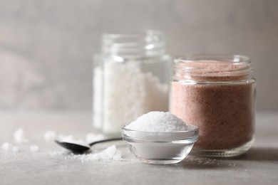 Photo of Different natural salt on grey table, closeup