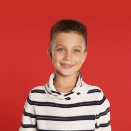 Cute little boy in sweater on red background. Winter season