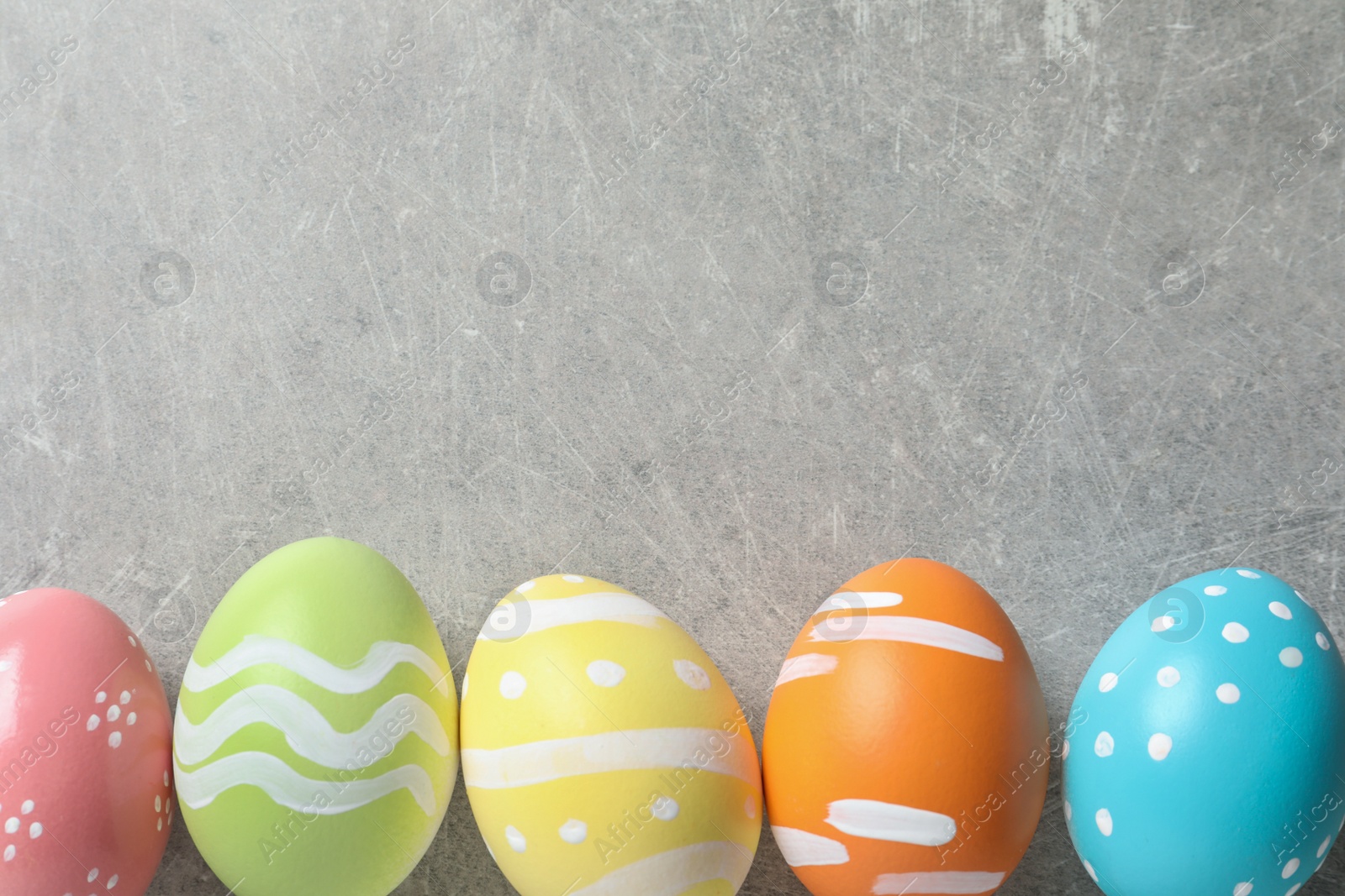 Photo of Flat lay composition of painted Easter eggs on color background, space for text