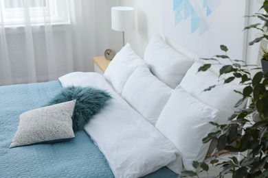 Photo of Comfortable bed with soft pillows in room interior