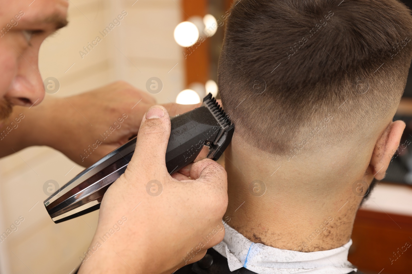 Photo of Professional hairdresser working with client in barbershop, closeup