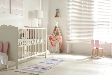 Photo of Cute baby room interior with crib and decor elements