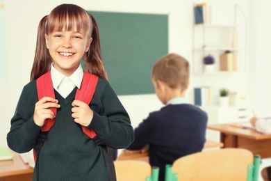 Image of Happy girl with backpack in school classroom