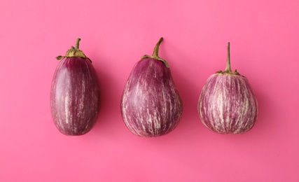 Photo of Raw ripe eggplants on pink background, flat lay