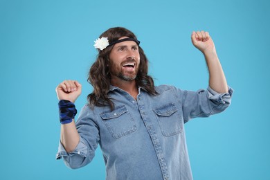 Photo of Cheerful hippie man dancing on light blue background