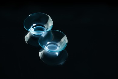 Pair of contact lenses on black background. Space for text