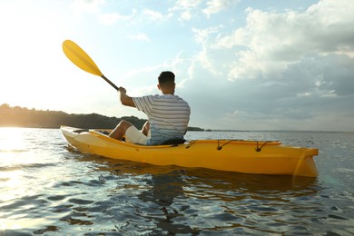 Photo of Handsome man kayaking on river, back view. Summer activity