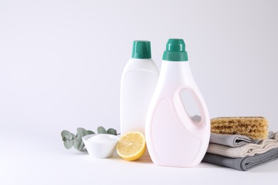 Bottles of cleaning product, brush, rags and lemon on light background