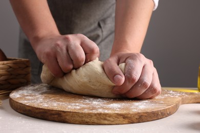 Man kneading dough at table near grey wall, closeup