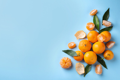 Photo of Fresh ripe tangerines on light blue background, flat lay. Space for text
