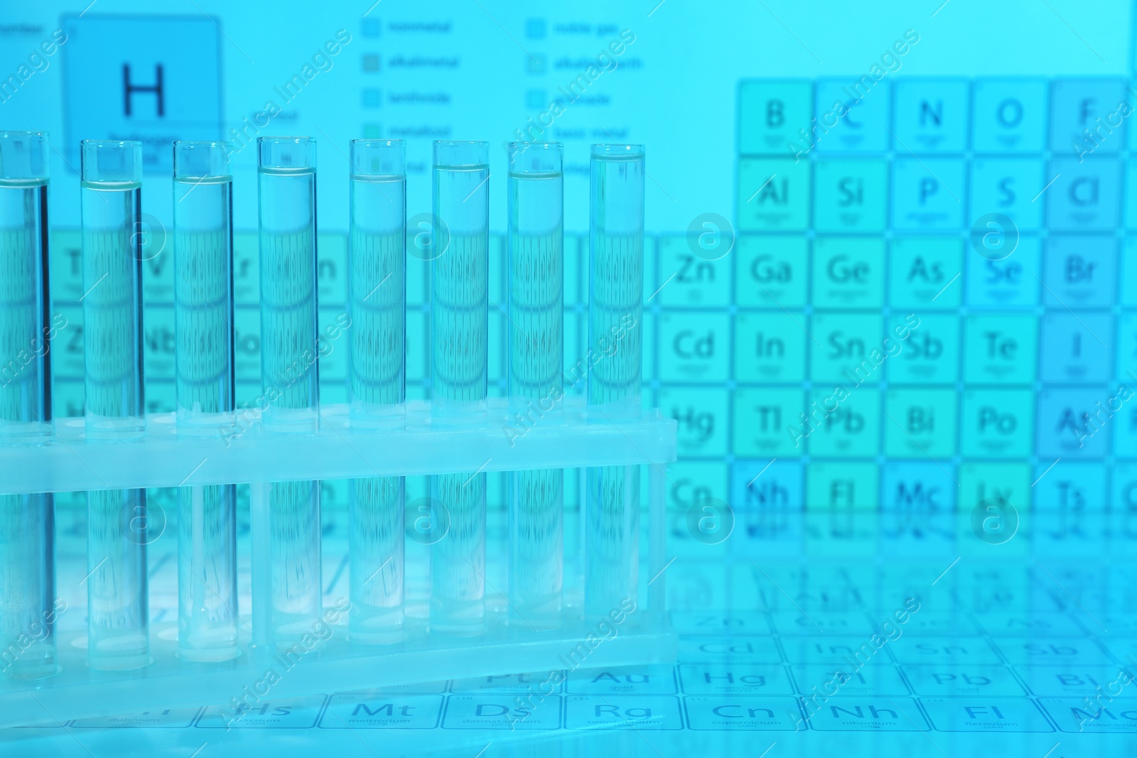 Photo of Test tubes against periodic table of elements, toned in light blue. Space for text