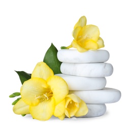 Stack of spa stones and freesia flowers on white background