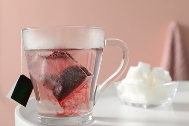 Photo of Tea bag in cup of hot water on white table